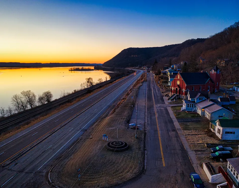 A breathtaking aerial view of Minneiska, MN at sunrise, featuring a highway by the Mississippi River.