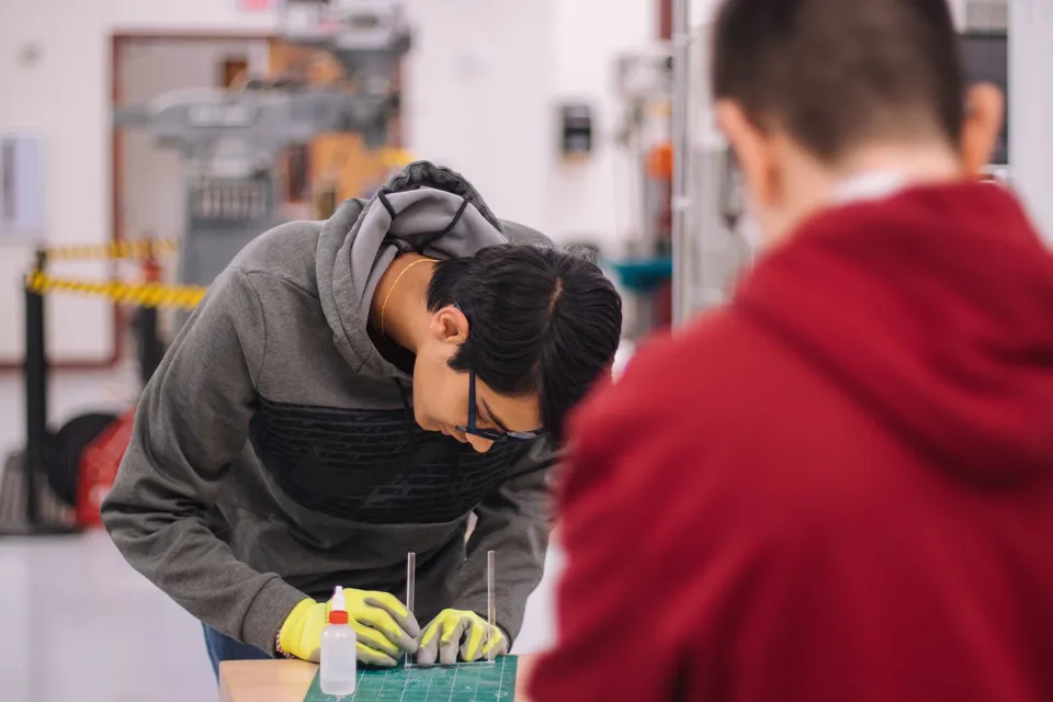 Two students working together in an engineering workshop with focus and precision.