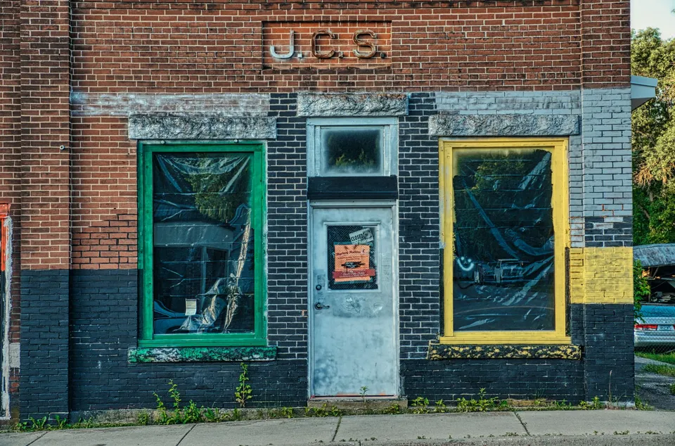 Old brick building with painted frames and closed door in Millville, MN.