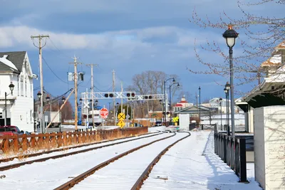 A scenic view of snow-covered train tracks in a small town setting during winter.